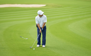 Fototapeta premium Asian golfer putting on green in summer vacation