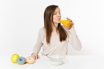 Woman sits at table breakfast with cereals and milk, drinks orange juice in glass, donuts isolated...