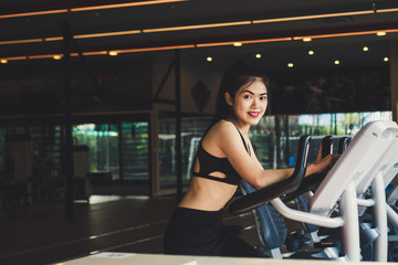 Asian fitness woman on bicycle doing spinning at gym. She looks healthy and happy to exercise. Medical and Healthy concept. Copy space.