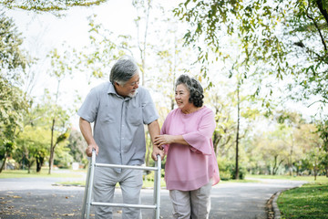 assisting her senior patient who's using a walker for support