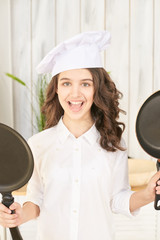 Young female chef with two pans.