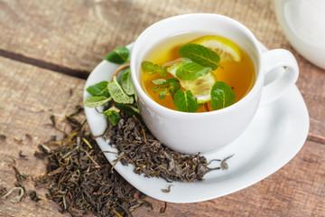 cup of black tea with mint leaves on a wooden table