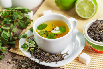 cup of black tea with mint leaves on a wooden table
