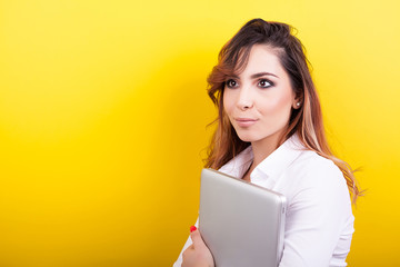 Student holds a laptop in her hands on yellow background