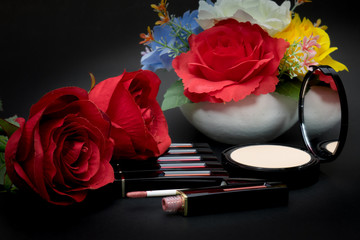 Lipstick,powder and flowers with cosmetics for women To make her look beautiful at work on a black background.