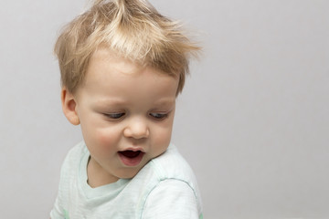 Naklejka premium Cute two years toddler in sleepwear on the grey background.