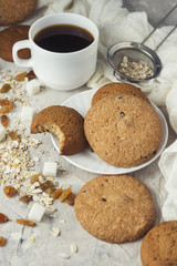 Cup of Black Coffee in a White cup, Oatmeal cookies, oatmeal, raisins on a light background. Breakfast Scene