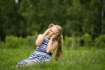 Smiling child girl wearing blue summer dress is playing in park