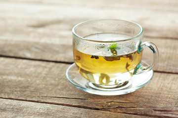 cup of black tea with mint leaves on a wooden table