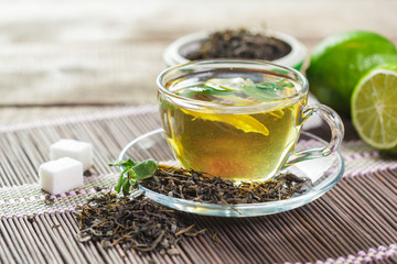cup of black tea with mint leaves on a wooden table