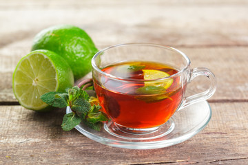 cup of black tea with mint leaves on a wooden table