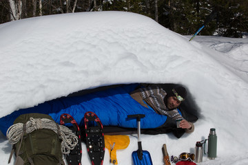 Man is lying in a snow cave, cross section