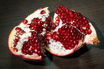 An opened ripe pomegranate fruit with red appetizing juicy seeds, seperating from the peel.