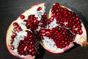 An opened ripe pomegranate fruit with red appetizing juicy seeds, seperating from the peel.