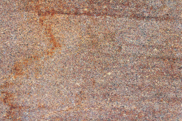 Red granite slab with stains close-up. Natural stone texture