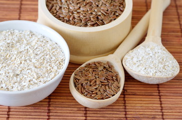 Flax seeds and oat bran in bowls and in wooden spoons