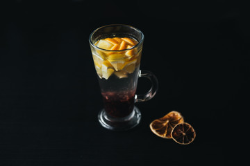 Traditional winter and autumn drinks. Christmas and Thanksgiving Cocktails. Mulled wine with orange, apple, rosemary, cinnamon and spices on a dark stone background, copy space top view