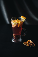 Traditional winter and autumn drinks. Christmas and Thanksgiving Cocktails. Mulled wine with orange, apple, rosemary, cinnamon and spices on a dark stone background, copy space top view