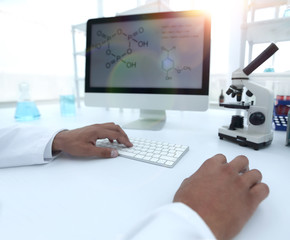 A scientist uses a computer and a microscope
