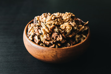 Walnuts kernels in wood bowl on dark desk, Walnut with color background, Whole walnuts in wood vintage bowl. rustic