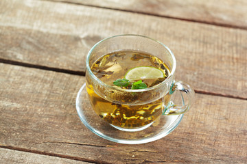 cup of black tea with mint leaves on a wooden table