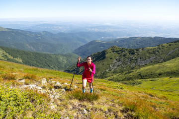 Fototapeta na wymiar Young woman in pink trekking in the mountain