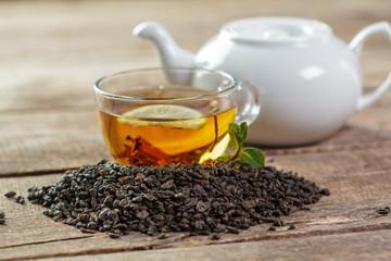 cup of black tea with mint leaves on a wooden table