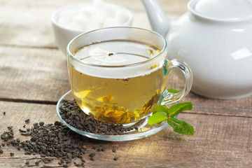 cup of black tea with mint leaves on a wooden table