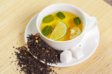 cup of black tea with mint leaves on a wooden table
