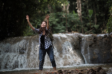 Young woman having fun under waterfalls in the forest