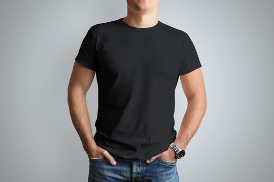 Front mockup black T-shirt on a young  guy isolated on a gray background.