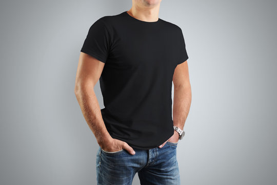 Mockup black T-shirts. A young athletic man is isolated on a gray background.
