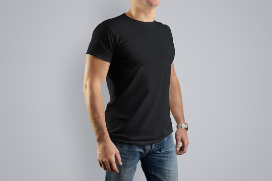 Mockup  black cotton T-shirt on a young guy posing on a gray background.