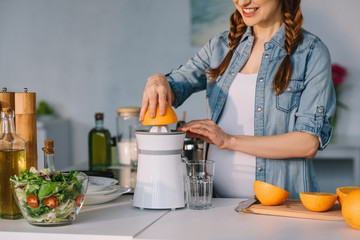 cropped image of attractive pregnant woman preparing homemade juice at kitchen