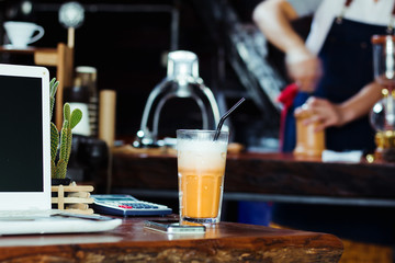 Computer and ice tea on wooden table at the coffee shop.