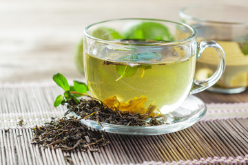 cup of black tea with mint leaves on a wooden table