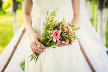 bride holds bridal bouquet of pink flovers