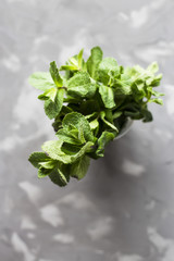 A green bunch of fragrant mint on a gray concrete background. Natural summer product. Top view