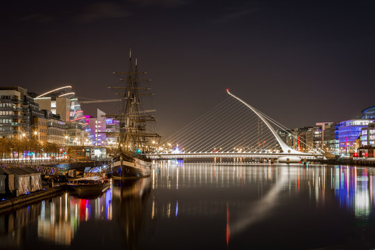 Beautiful night view of Dublin with water, bridge and buildings.