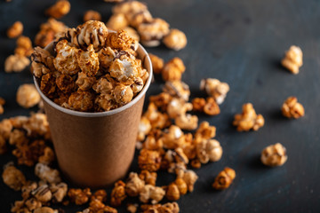 Diverse Popcorn in a paper cup against a dark background.