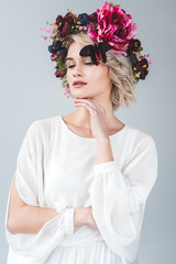 tender woman posing in floral wreath with butterfly, isolated on grey