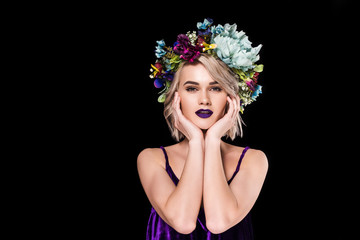 blonde girl posing in purple dress and floral wreath, isolated on black