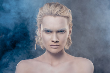 Fototapeta premium portret modnej blondynki z białym makijażem w zadymionym studio