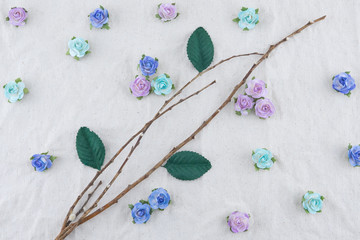 Brown branch decorate with blue tone rose paper flowers and green leaves on muslin fabric with copy space