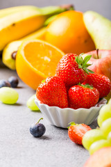 Fresh assorted fruits and berries on light gray background. Colorful clean and healthy eating. Detox food. Copy space.