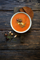 Tomato soup with cheese, olives and herbs. Dark wooden background

