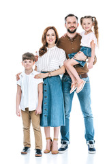 full length view of happy family with two children standing together and smiling at camera isolated on white