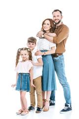Fototapeta na wymiar full length view of happy family with two children standing together and smiling at camera isolated on white