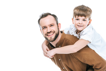 happy father piggybacking little son and smiling at camera isolated on white