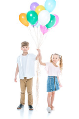 adorable happy siblings holding colorful balloons and smiling at camera isolated on white